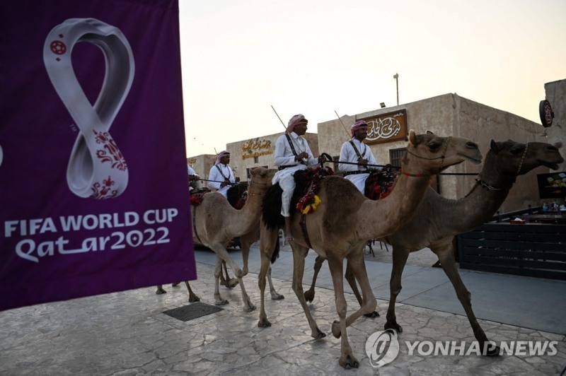 낙타를 탄 카타르 주민들이 올림픽을 알리는 광고판을 지나가고 있다. [사진=연합뉴스]  