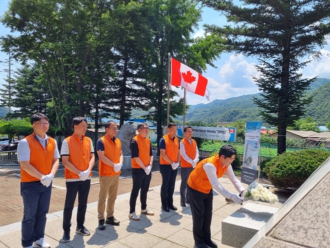 한화오션 직원들이 24일 경기도 가평군 북면에 위치한 캐나다 전투기념비에 헌화하고 있다. [사진=한화오션]
