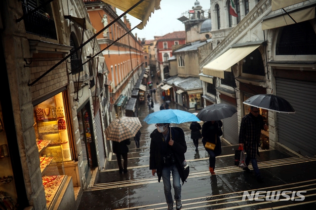 1일(현지시간) 이탈리아 북부 베테토주에 비가 오는 가운데 리알토 다리에서  시민들이 마스크를 착용하고 우산을 쓴 채 걷고 있다. 이 지역에서는 신종 코로나바이러스 감염증(코로나19) 확진자가 다수 나왔다. 