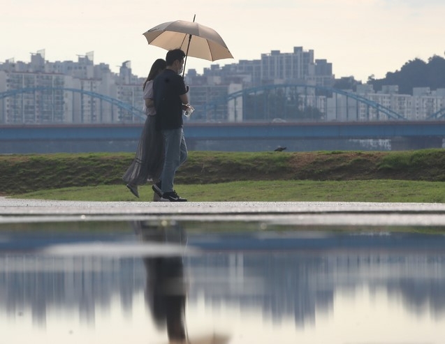 폭염 속 소나기가 내린 지난 15일 서울 서초구 반포지구 한강공원에서 시민들이 우산을 쓰고 걸어가고 있다.