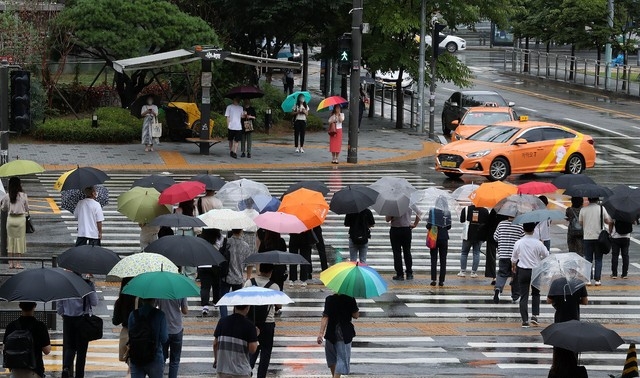 출근길 비가 내린 지난 18일 오전 서울 용산역 앞 시민들이 횡단보도 신호를 기다리고 있다. 