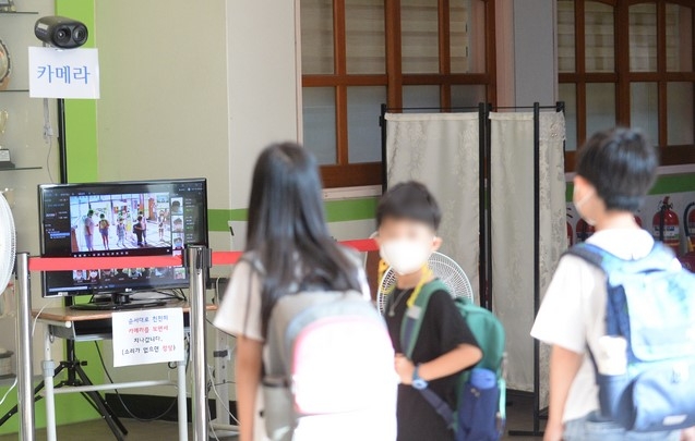 코로나19 속 2학기 전면등교가 시작된 18일 오전 광주 북구 동림초등학교에서 학생들이 등교하기 앞서 발열 확인을 하고 있다.