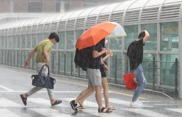 제주국제공항에서 관광객들이 비를 피해 렌터카 보관소로 이동하고 있다.
