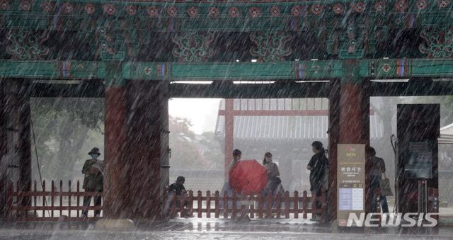 전북 전주시에 갑작스러운 집중호우가 내린 지난 12일 오후 전주한옥마을 경기전 처마 밑에서 관광객들이 비를 피하고 있다.