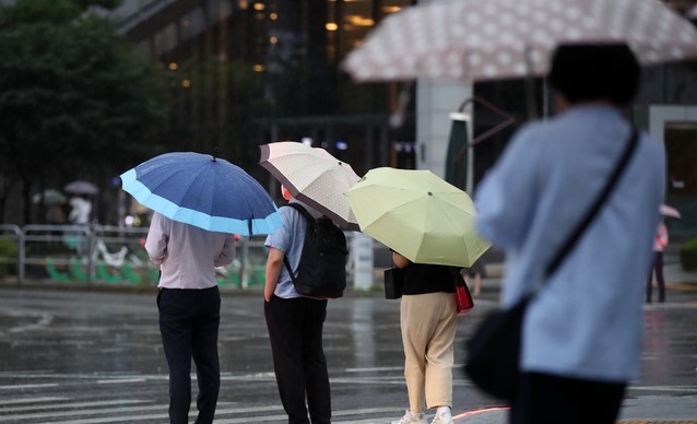 제12호 태풍 '오마이스'가 우리나라를 향해 북상하고 있는 23일 오후 서울 중구의 한 도로에서 시민들이 우산을 쓰고 지나가고 있다. 