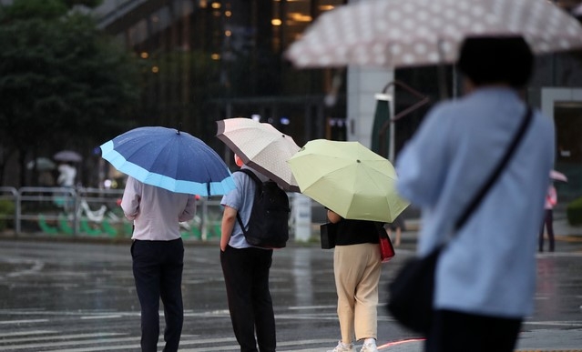 제12호 태풍 '오마이스'가 우리나라를 향해 북상하고 있는 23일 오후 서울 중구의 한 도로에서 시민들이 우산을 쓰고 지나가고 있다. 