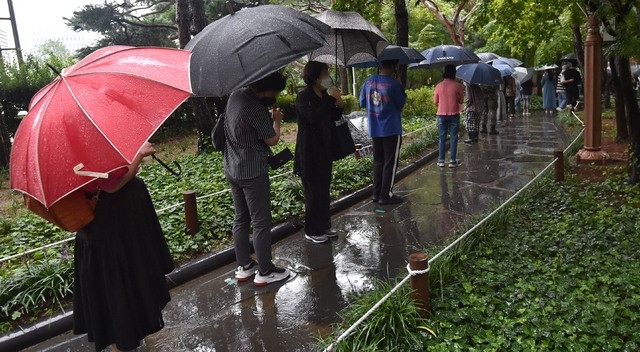  비가 내리고 있는 24일 대구 중구 국채보상운동기념공원 코로나19 임시선별검사소에서 시민들이 검사를 받기 위해 우산을 쓰고 긴 줄을 서고 있다.