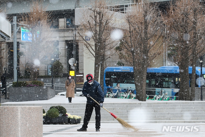 눈이 내리고 있는 지난 6일 오전 서울 중구 서울역 인근 빌딩에서 관계자가 눈을 치우고 있다.