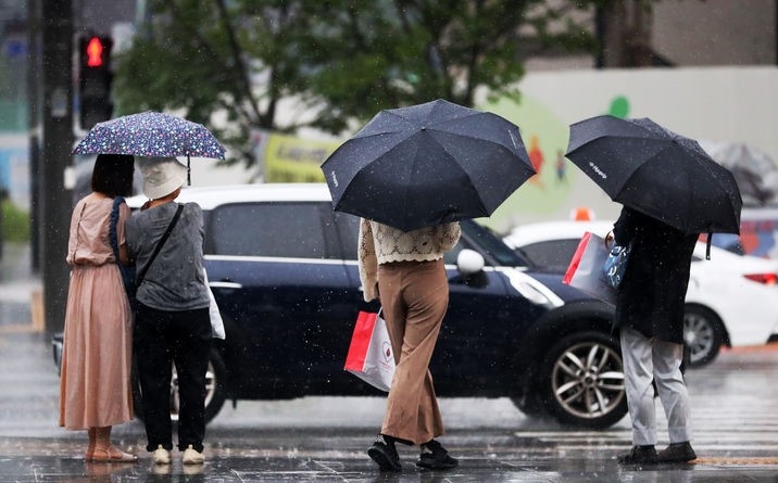  강한 소나기가 내린 지난 14일 오후 서울 종로구 광화문 광장에서 우산을 쓴 시민들이 횡단보도 신호를 기다리고 있다. 