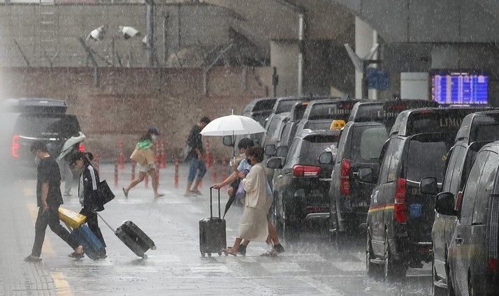  제주국제공항에서 관광객들이 비를 피해 이동하고 있다.