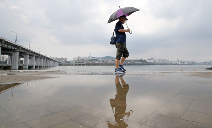 소나기가 내린 지난 6일 오후 서울 서초구 반포 한강공원에서 시민이 우산을 쓰고 이동하고 있다. 