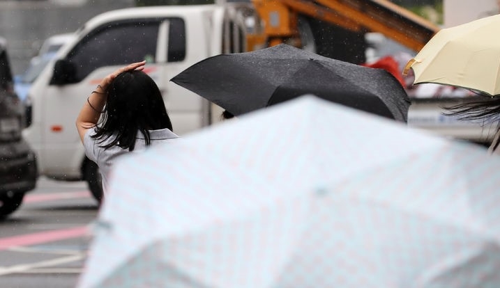  어제(21일) 오후 서울 광화문 사거리에서 한 시민이 손으로 비를 막은 채 횡단보도 신호를 기다리는 모습.