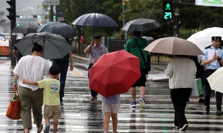 비가 내린 지난 22일 오후 서울 종로구 광화문 네거리에서 한 아이가 엄마와 함께 우산을 쓰고 이동하는 모습. 