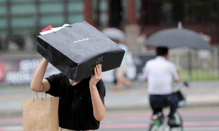 지난 21일 오후 서울 광화문 사거리에서 한 시민이 쇼핑백으로 비를 막은 채 발걸음을 옮기고 있는 모습. 