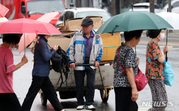 지난 13일 오후 서울 시내 한 대로변에서 노인이 폐지를 리어카에 싣고 발걸음을 재촉하고 있는 모습.