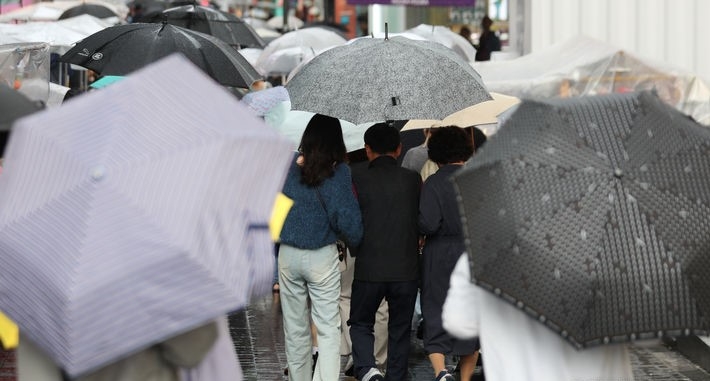  추석 연휴 셋째 날인 지난달 30일 서울 중구 명동에서 시민들과 외국인들이 우산을 쓴 채 내리는 비를 맞으며 이동하고 있다.