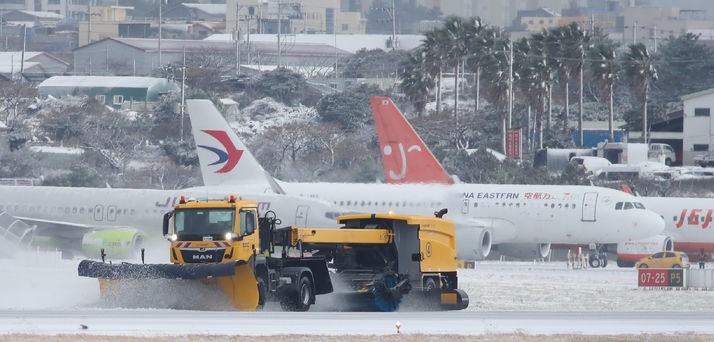 북극 한파 영향으로 전국 기상이 악화한 21일 오후 제주국제공항 활주로에서 제설차량들이 부지런히 쌓인 눈을 치우고 있다. 