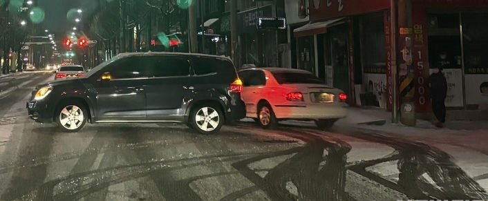 광주지역에 대설경보가 내려진 23일 오전 광주 북구 한 도로에서 SUV 차량이 눈길에 미끄러져 사고를 수습하고 있다.
