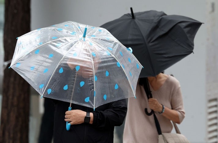 비가 내린 지난 6일 오후 서울 중구 세종대로 사거리 인근에서 우산을 쓴 시민이 우산으로 바람을 막으며 발걸음을 옮기는 모습.