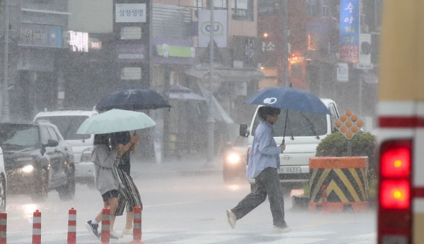 정체전선이 북상하며 호우경보가 내려진 지난 20일 오후 제주 서귀포시 서홍동 인근 횡단보도에서 우산을 쓴 시민들이 걸어가고 있다. 