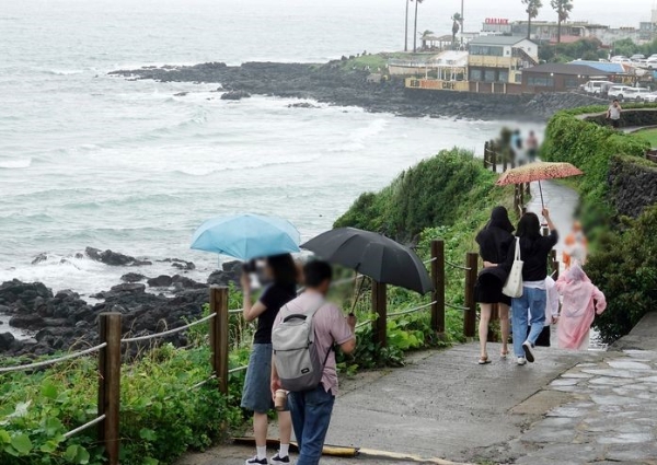  장맛비가 내리는 지난 6월30일 오후 제주시 애월읍 한담공원에서 우산을 쓴 관광객들이 산책하고 있다.