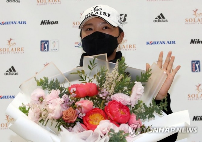 미국여자프로골프(LPGA) 투어 2021시즌 상금왕과 올해의 선수 부문을 석권한 고진영이 23일 오후 인천 영종도 인천국제공항 제2여객터미널을 통해 귀국한 뒤 꽃다발을 받고 손을 흔들고 있다. [영종도=연합뉴스]