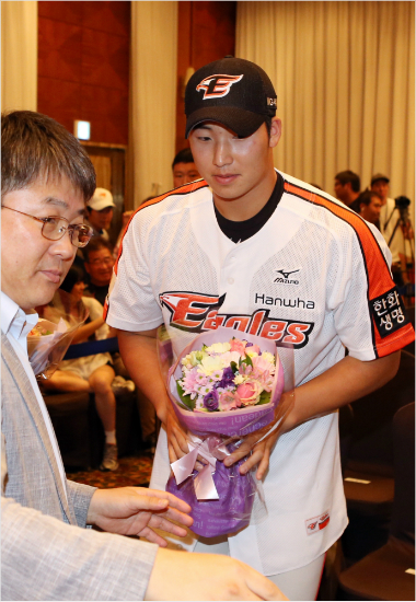 '제2의류현진이돼주게'마산용마고우완김민우(오른쪽)가25일2015프로야구신인2차지명회의에서1순위로한화유니폼을입은뒤노재덕단장으로부터꽃다발을받고있다.(사진=한화이글스)