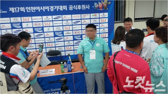 2014인천아시안게임유도종목이열리는인천도원체육관의한자원봉사자가몽골출신의메달리스트를배경으로기념사진을촬영하고있다.(노컷뉴스DB)