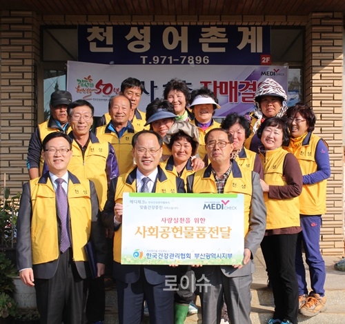 ▲부산가덕도천성마을을찾아자매결연을체결한뒤행사의류100벌을전달하고기념촬영.<건협부산센터제공>