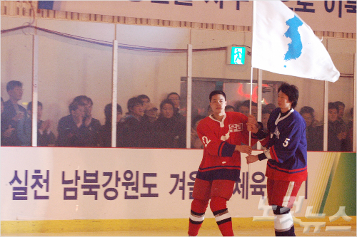 2006년3월3일강원도춘천의암빙상장에서열린남북아이스하키친선경기개회식에서북측대표리금송(왼쪽.우리팀)과남측대표표장원(하나팀)이대형한반도기를흔들고있다.