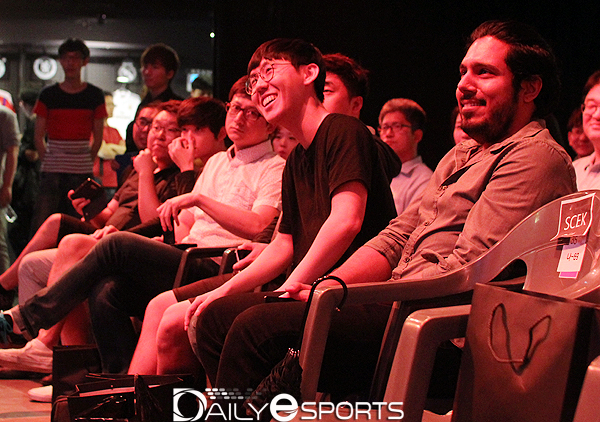 김현진이 무대에 선 선수들과 눈을 마주치며 웃고 있습니다.