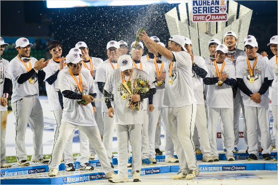 '이순간진정한원팀!'두산선수단이삼성을꺾고한국시리즈정상에오른뒤시상식에서김태형감독(앞중간)에대해김현수(앞오른쪽)와양의지가샴페인세례를퍼붓는모습.(잠실=두산베어스)