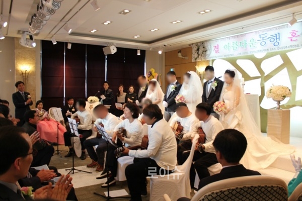 ▲합동결혼식에서기타연주를선보이고있다.▲합동결혼식에서3쌍의가정을축복하며기념촬영을하고있다.(사진제공=한국법무보호복지공단경남서부지소)