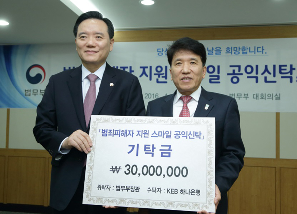 김현웅법무부장관이20일정부과천청사대회의실에서열린범죄피해자지원스마일공익신탁출범식에서함영주KEB하나은행장에게기탁금을전달하고있다.(사진=법무부)