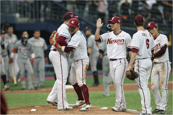 '부자인패자와승자의기쁨'서건창이9회자신의실책에도승리를지켜준마무리김세현을껴안는등넥센선수들이경기후서로격려하는모습.뒷편으로한화선수들이팬들에게인사하기위해그라운드로나오고있는모습.(고척=넥센)