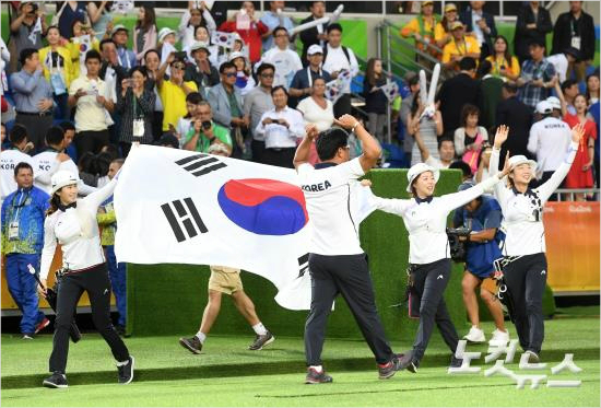 여자양궁기보배(왼쪽부터),장혜진,최미선이7일오후(현지시간)브라질리우데자네이루마라카낭삼보드로무양궁장에서열린2016리우올림픽양궁여자단체전결승전에서러시아에승리해금메달을확정짓고양창훈감독과함께태극기를들고응원단에인사하고있다.(리우=올림픽사진공동취재단)