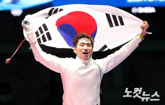 펜싱대표박상영이9일(현지시간)브라질리우데자네이루바하올림픽파크카리오카경기장에서열린펜싱남자에페결승에서헝가리의임래게자와경기에승리한후태극기를들고환호하고있다.박상영은15-14로대역적승을거두며한국선수단세번째금메달을획득했다.(올림픽사진공동취재단)