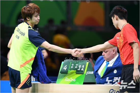 "다음에는내가이긴다."정영식(왼쪽)이단체전4강에서장지커에게진뒤악수하는장면.(올림픽사진공동취재단)