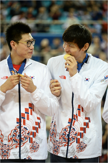 동부김주성(사진오른쪽)이2014인천아시안게임남자농구시상식에서팀동료오세근을바라보며금메달을깨물고있다(사진제공=KBL)