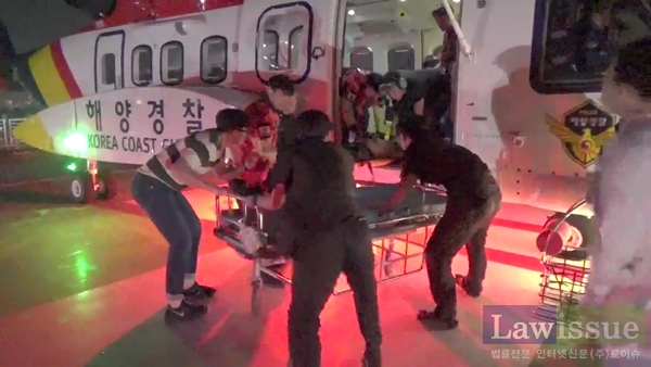 의식불명환자를 대형헬기에 옮기고 있다.