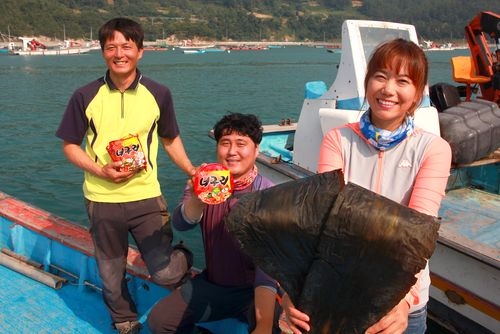 금일도 어민들이 다시마와 너구리를 들고 있다(사진 =농심)