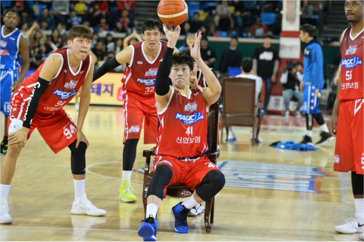 오세근 매직 팀의 오세근이 '왕좌의 게임' 이벤트에서 앉아서 외곽슛을 쏘는 이벤트를 하고 있다. 최준용, 이종현이 곁에서 그 모습을 바라보고 있다 (사진 제공=KBL)
