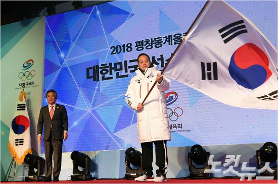 24일 오후 서울 올림픽파크텔에서 열린 2018 평창동계올림픽 선수단 결단식에서 김지용 선수단장이 이기흥(왼쪽) 대한체육회장에게 전달받은 태극기를 흔들고 있다. 박종민기자