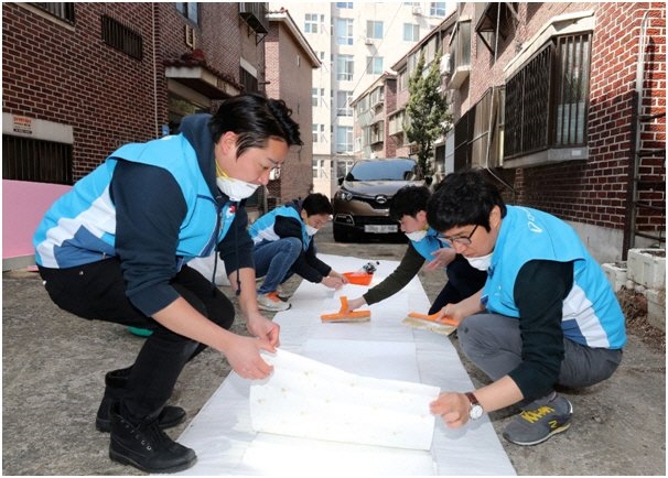지난 22일 서울 마포구에서 대우건설 임직원들이 노후주택에 도배할 벽지에 풀을 바르고 있다. (사진=대우건설)