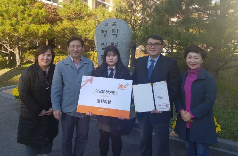 (사진=bhc치킨이 지난 2일 ‘이달의 bhc히어로’로 선정된 황현희(가운데) 양에게 문상만(오른쪽에서 두 번째) 이사가 상장을 전달한 후 선생님들과 함께 기념촬영을 하고 있다.)