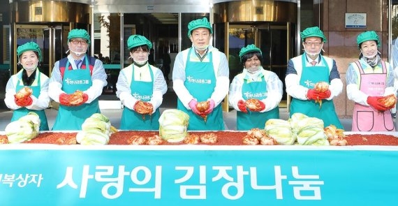 (사진=김정태 하나금융그룹 회장(왼쪽 네번째)이 정연보 서울특별시 사회복지협의회장(왼쪽 여섯번째), 황성욱 롯데제과 재경팀 상무(왼쪽 두번째), 다문화 이주 여성, 가족사랑봉사단원들과 소외계층에 전달할 ‘사랑의 김장’을 담그고 있다./하나금융그룹 제공)