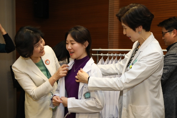 사진=이선영 진료부원장과 현석경 간호부원장이 신입 인턴에게 의사 가운을 입혀주고 있다.