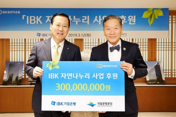 12일 을지로 기업은행 본점에서 김도진 기업은행장(왼쪽)과 권경업 국립공원공단 이사장이 ‘IBK 자연나누리 사업’ 후원금 전달식을 마치고 기념촬영을 하고 있다.