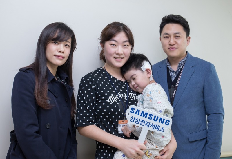 삼성전자서비스의 후원으로 인공달팽이관 수술을 받은 아동과 어머니(가운데)를 격려 방문한 사랑의달팽이 재단 관계자(좌)와 삼성전자서비스 한마음협의회 오지상 대표위원(우)이 기념 사진 촬영을 하고 있다./삼성전자서비스 제공