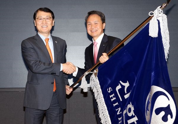 26일 서울 중구 세종대로 소재 신한은행 본점에서 진행된 취임식에서 진옥동 신한은행장이 위성호 전 행장으로부터 은행기를 전달받으며 악수하는 모습. 사진=신한은행